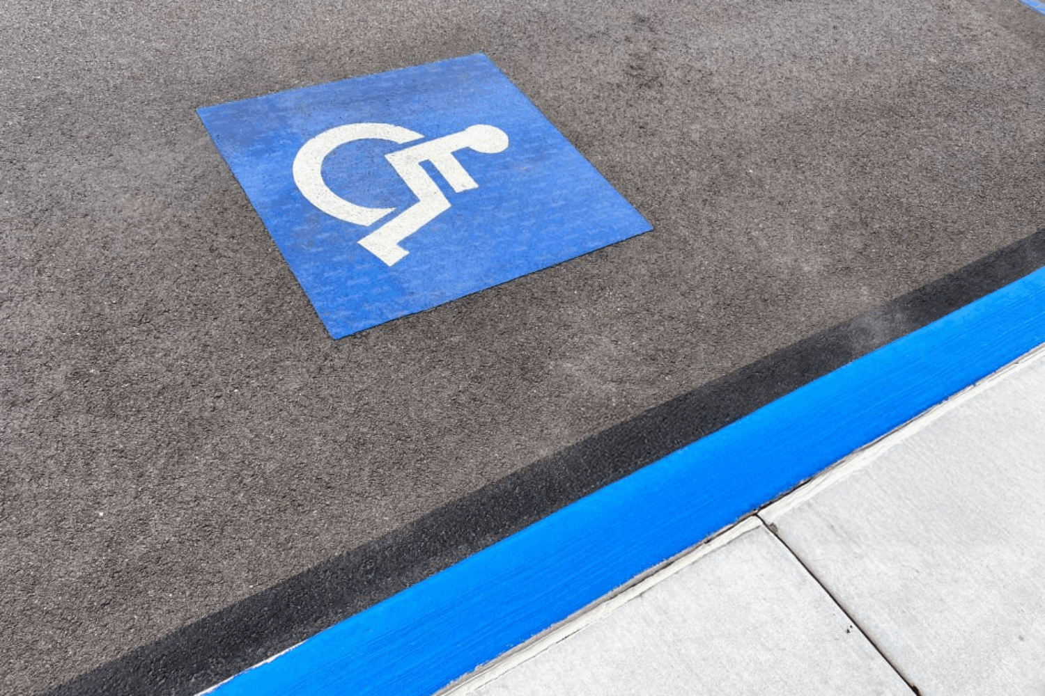Handicapped parking space marked by handicap logo and blue curb