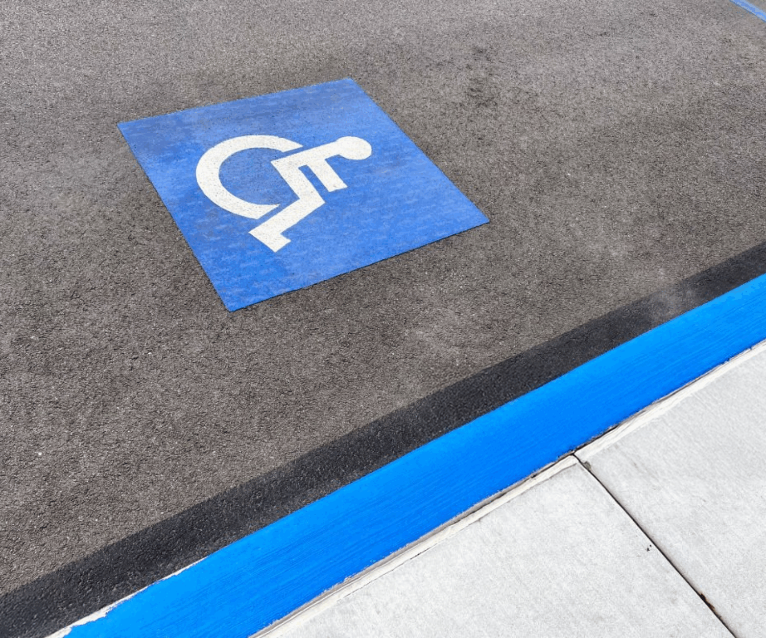 Handicapped parking space marked by handicap logo and blue curb