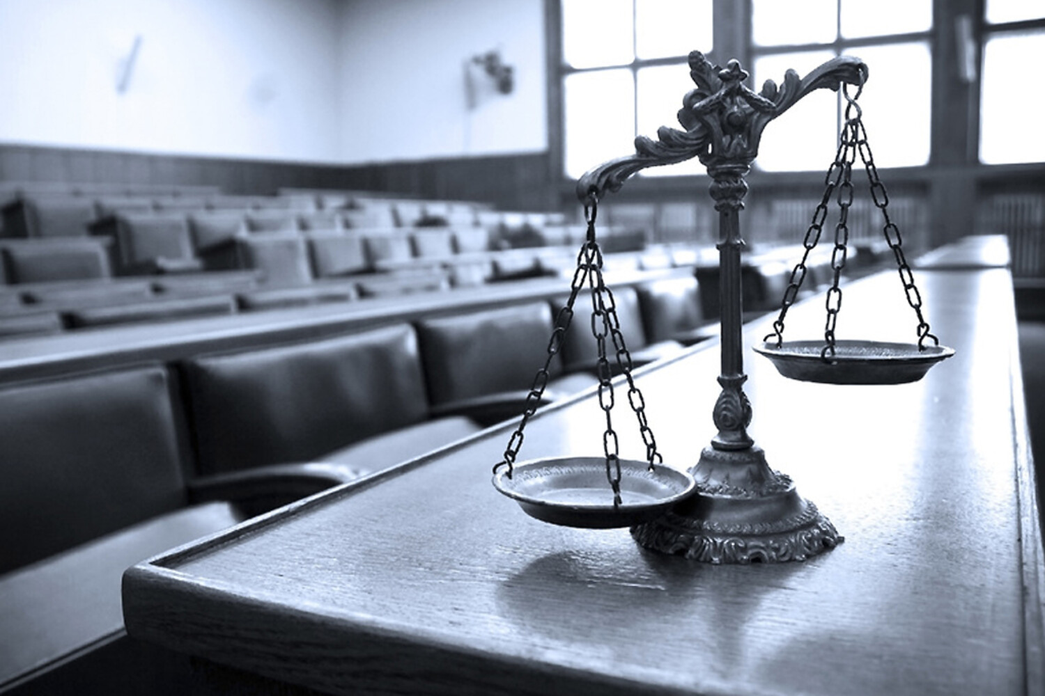 A scale on a table in front of a row of chairs, indicating a court room appearance